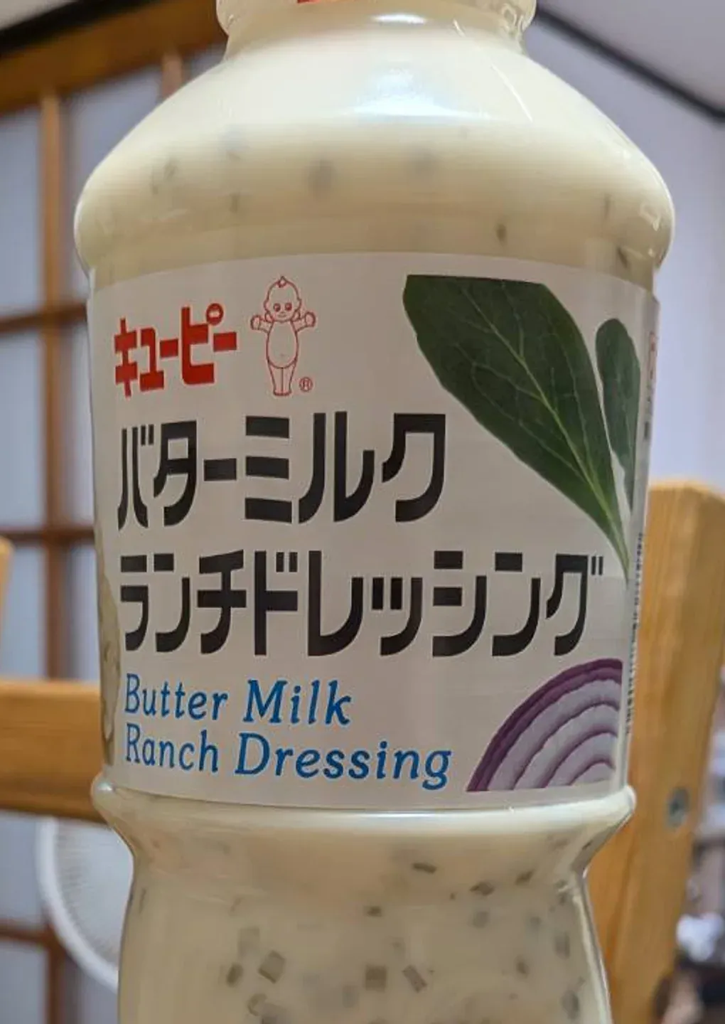 キユーピー バターミルクランチドレッシングの1Lボトル。乳白色のドレッシングに緑のハーブが散っている